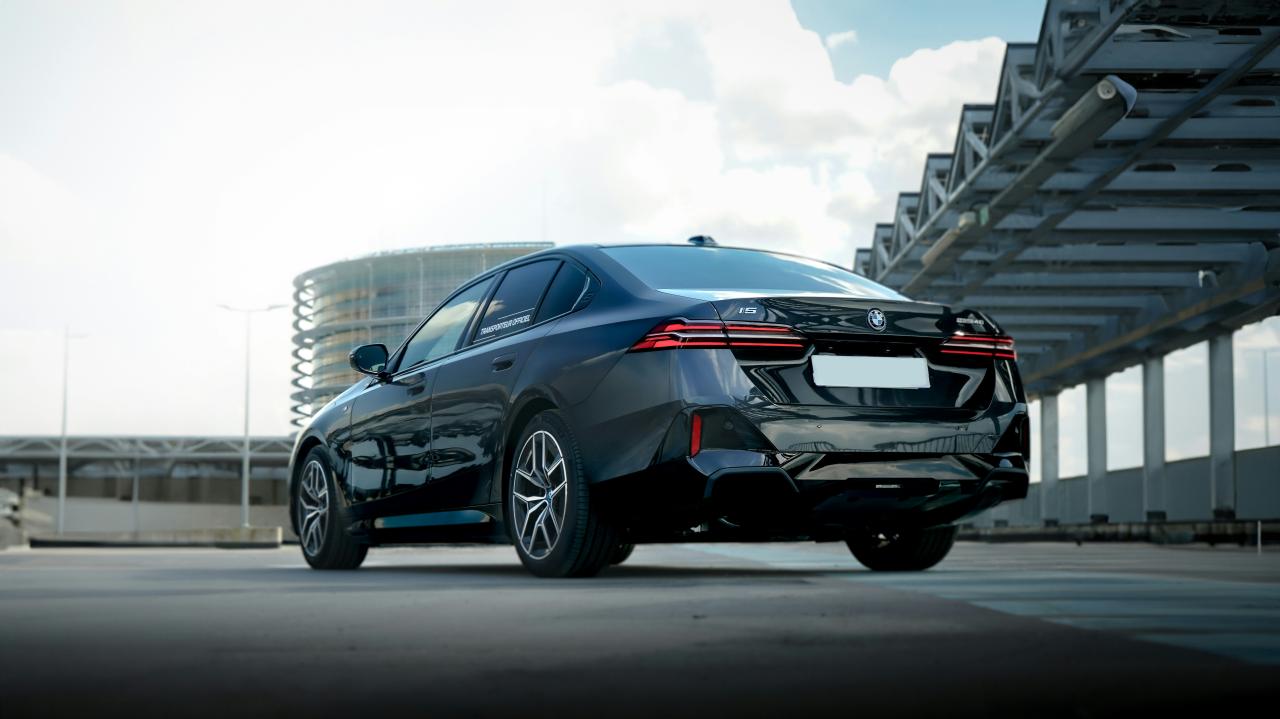 Dark sedan parked outdoors under bright sky.