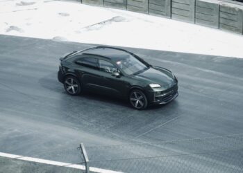 Sebuah mobil hitam melaju di jalan di sebelah pagar