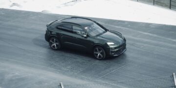 Sebuah mobil hitam melaju di jalan di sebelah pagar